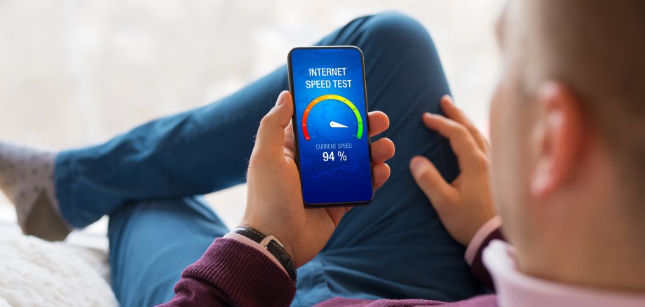Ein Mann checkt die Geschwindigkeit der Internetverbidung mit einer App auf seinem Handy.