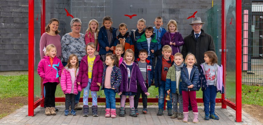 Das Kinderparlament der Kindertagesstätte Abenteuerland in Boppard-Buchholz freut sich gemeinsam mit ihren Erzieherinnen (obere Reihe, von links) Simone Nowak und Karolin Weber und Boppards Bürgermeister Jörg Haseneier (obere Reihe, rechts) über das neu errichtete Bushäuschen. 