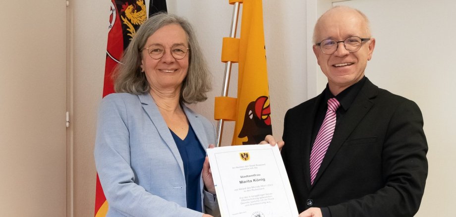 Das Foto zeigt Bürgermeister Jörg Haseneier bei der Verabschiedung der Leiterin des Standesamts und Bürgerbüros. Der Bürgermeister überreicht die Entlassurkunde,