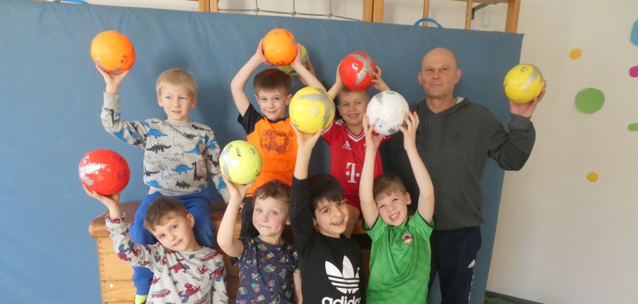 Das Foto zeigt die Kita-Kinder mit den neuen Bällen und ihren Trainer Frank Gutmann vom SC Weiler.