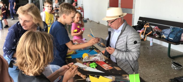 Arthur erklärt dem Bürgermeister sein Bastelwerk, das bei der Sommerferienaktion entstanden ist.