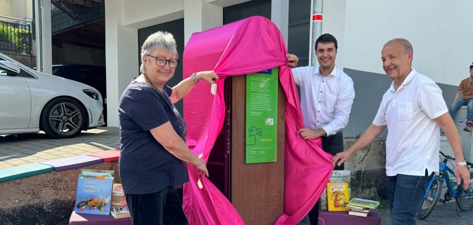 Bei strahlendem Sonnenschein enthüllten Bücherpatin Marga Stelzer, Westenergie-Regionalmanager Florian Schmidt (Mitte) und Ortsvorsteher Andreas Mayer den 355. Westenergie Bücherschrank in Weiler bei Boppard. 