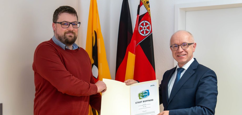 Boppards Bürgermeister Jörg Haseneier (rechts) und Klimaschutzmanager Dominik Nachtsheim mit der Urkunde für 30 Jahre Mitgliedschaft im Klima-Bündnis.