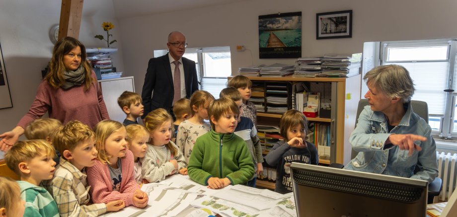 In der Bauverwaltung bestaunten die Kinder die Architektenpläne ihrer Kindertagesstätte, Sachgebietsleiterin Angela Wolf (rechts) erklärte ihnen, welche Arbeiten in einer Bauverwaltung anfallen und dass Architektenpläne früher per Hand und heute am Computer gezeichnet werden.